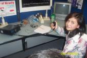 A girl holding a microphone next to a radio inside.